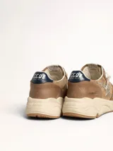 Zapatillas Golden Goose modelo Running Sole, color marrón con detalles en plateado y azul. Confeccionadas en cuero y gamuza, con cordones con letras y estrella plateada con glitter en el lateral.