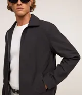 Campera negra de algodón con cuello inglés, cierre con cremallera, manga larga con ajuste fruncido elástico en el bajo trasero y bolsillos laterales.