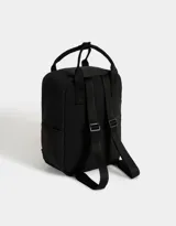 Mochila negra de tela deportiva con correas regulables, manijas superiores con broche, acceso con cierre superior y puller de cuerina, bolsillo frontal con cierre y puller de cuerina, y tag de goma.