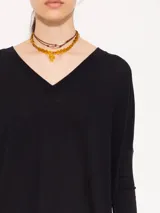 Remera negra de punto liviano con escote en V, mangas 3/4 y recortes diagonales en el delantero.