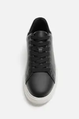 Zapatillas deportivas negras con detalle en blanco en la parte posterior y suela blanca con volumen de diseño irregular.