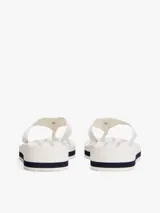 Ojotas de mujer con plataforma de cuña, tiras anchas de tejido trenzado y monograma TH en la tira del dedo. La plataforma es blanca con una línea decorativa azul marino.