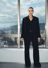 Blazer negro de corte entallado con solapas de muesca, cierre cruzado con un botón, bolsillos delanteros con solapa y manga larga con puños abotonados.