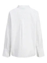 Camisa blanca de corte oversize con cuello clásico, cierre frontal con botones y pequeños brillantes plateados distribuidos por toda la prenda.