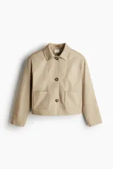 Campera color beige de corte holgado en sarga de algodón. Modelo con cuello, cierre de botones y bolsillos parche delanteros.