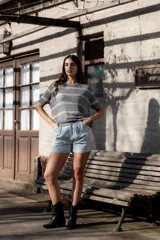 Remera de punto gris con rayas horizontales celestes, corte recto y mangas cortas.