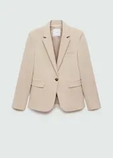 Blazer color beige con cuello de pico con solapa, hombros estructurados, cierre de botón en la parte delantera y dos bolsillos de ribete en la parte delantera.