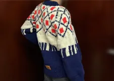 Sweater de lana merino con cuello redondo y diseño con motivos geométricos en tonos azul, marrón, naranja, verde y beige.