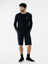 Camiseta blanca de manga larga con estampado rectangular con imagen de playa y edificio.