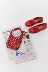 Mocasín de cuero color marrón claro, con detalle de flecos y borlas en la parte delantera. Diseñado en Uruguay y fabricado en Brasil.