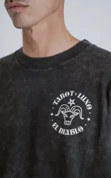 Remera negra con efecto nevado, corte oversize y estampa sublimada en la espalda con la carta del tarot 'El Diablo'.