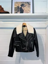Chaqueta de cuero con cuello desmontable de pelaje, cierre frontal y detalles de bolsillos.