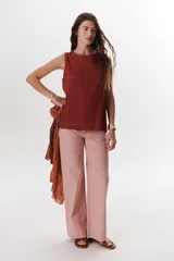 Top sin mangas color terracota con cuello redondo y bolsillo frontal. Presenta costuras a contratono en blanco que definen los bordes y el bolsillo.