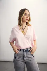 Blusa rosa de lino con escote cruzado en V y mangas cortas. Incluye un collar con cordón negro y dije dorado.