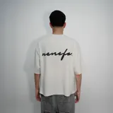Remera blanca de algodón con corte oversize y estampado con la palabra 'nenefa' en cursiva negra en la espalda.