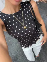 Top negro con lunares blancos, sin mangas, con escote redondo y detalle de fruncido en la cintura.