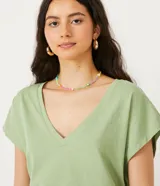 Blusa verde de algodón con escote en V y mangas cortas.
