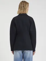 Blazer azul marino de tejido de punto milanés, con solapas de muesca, cierre frontal de dos botones y bolsillos de ojal. Presenta un patrón de rayas finas verticales (pinstripe).