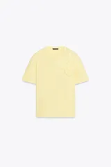 Camiseta de algodón color amarillo pálido, de corte recto, cuello redondo y manga corta. Presenta apliques de flores en relieve en el frente.