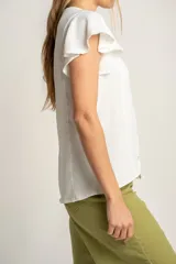 Blusa blanca con escote en V, mangas cortas con volados y cierre frontal con botones.