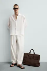 Camisa de manga larga color celeste claro, con cuello solapa y cierre frontal de botonadura. Presenta una textura sutil en el tejido.