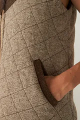 Chaleco corto de lana color marrón con diseño acolchado en forma de rombos. Presenta cuello alto, cierre frontal con cremallera dorada, dos bolsillos laterales y canesú en color marrón oscuro. Hecho en Uruguay.