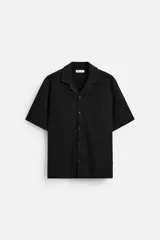 Camisa negra de manga corta con cuello bowling, corte regular y bajo con aberturas laterales.