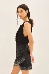 Minifalda negra con lentejuelas y piedras bordadas, de tiro medio y corte irregular.