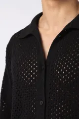 Camisa negra tejida de manga corta, con calado aireado, cuello tipo bowling y botones al tono. Diseño de corte relajado.