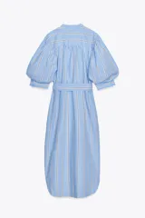 Vestido midi de algodón a rayas celestes y blancas con cinturón de la misma tela, cuello redondo, manga abullonada con puño y cierre frontal con botones.