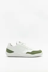 Zapatillas de cuero color blanco y beige, de diseño minimalista con suela marrón.
