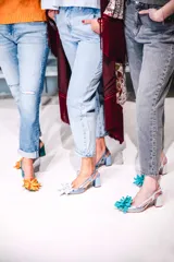 Zapato de tacón plateado con diseño de escamas y flor turquesa en la punta.