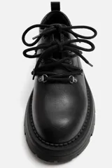 Zapato tipo derby de cuero negro con cordones y ganchos metálicos. Suela track con plataforma.