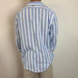 Camisa de lino a rayas verticales color beige y blanco, de corte holgado y manga larga con puños abotonados.