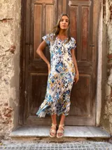 Vestido midi con estampado abstracto en tonos azules, camel y blanco. Tiene mangas cortas con volados y escote en V.
