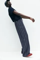 Pantalón de corte holgado en tejido liviano de mezcla de lino a rayas verticales blancas y azul marino. Modelo de tiro alto con cintura elástica y cordón para ajustar fino, bolsillos laterales discretos y piernas rectas.