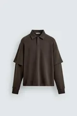 Polo marrón de corte relaxed fit confeccionado en tejido de algodón. Tiene cuello solapa con cierre frontal de botonadura y manga larga con efecto doble manga.
