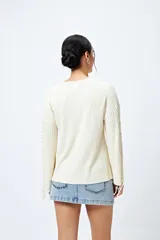 Sweater negro de punto canalé con detalle de trenzado en las mangas y lazo ajustable en el ruedo.