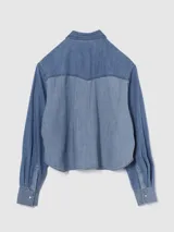 Camisa corta de jean celeste con dos bolsillos frontales con solapa y cierre con botones a presión.