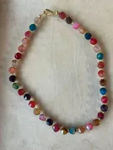 Collar de cuentas facetadas en tonos pastel como blanco, naranja, azul y gris.