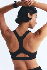 Top deportivo negro de tejido funcional con tecnología ShapeMove™ y DryMove™. Ofrece ajuste ceñido y soporte óptimo. Copas forradas con relleno extraíble, breteles anchos ajustables, espalda nadadora en malla con sección cut-out y cierre de corchetes atrás.