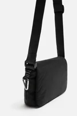 Bandolera negra de nylon con solapa y cierre magnético. Tiene correa ajustable con mosquetón y bolsillo interior.