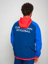 Campera deportiva con capucha, azul con mangas celestes y detalles en rojo. Escudo del Club Nacional de Football bordado en el pecho.
