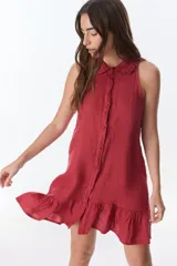 Vestido corto color ladrillo, sin mangas, con cuello camisero con volados, abotonado al frente y falda con volados.