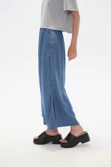 Pantalón capri de denim azul con cintura elástica y aberturas laterales en el ruedo.