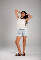 Blusa blanca de crochet calado, sin mangas y con cuello redondo con ribete negro.