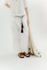 Pantalón blanco de lino y algodón, de tiro medio, con pinzas frontales, pretina ancha en la espalda con cambio de color y vivo en contratono, cortes en la mitad de la pierna de la espalda, cierre frontal con cierre y botón, y bolsillos delanteros.