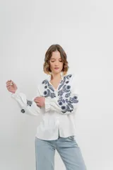 Camisa de manga larga en algodón liviano, color azul marino, con bordados florales en contraste en el frente y mangas. Cuello mao con terminación en ondas y puños fruncidos.