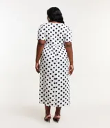 Vestido midi blanco con lunares negros, de corte suelto, cuello redondo y mangas cortas.