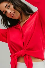 Camisa roja de crepé fluida con cuello camisero, mangas largas con puños abotonados y cierre frontal con botones.